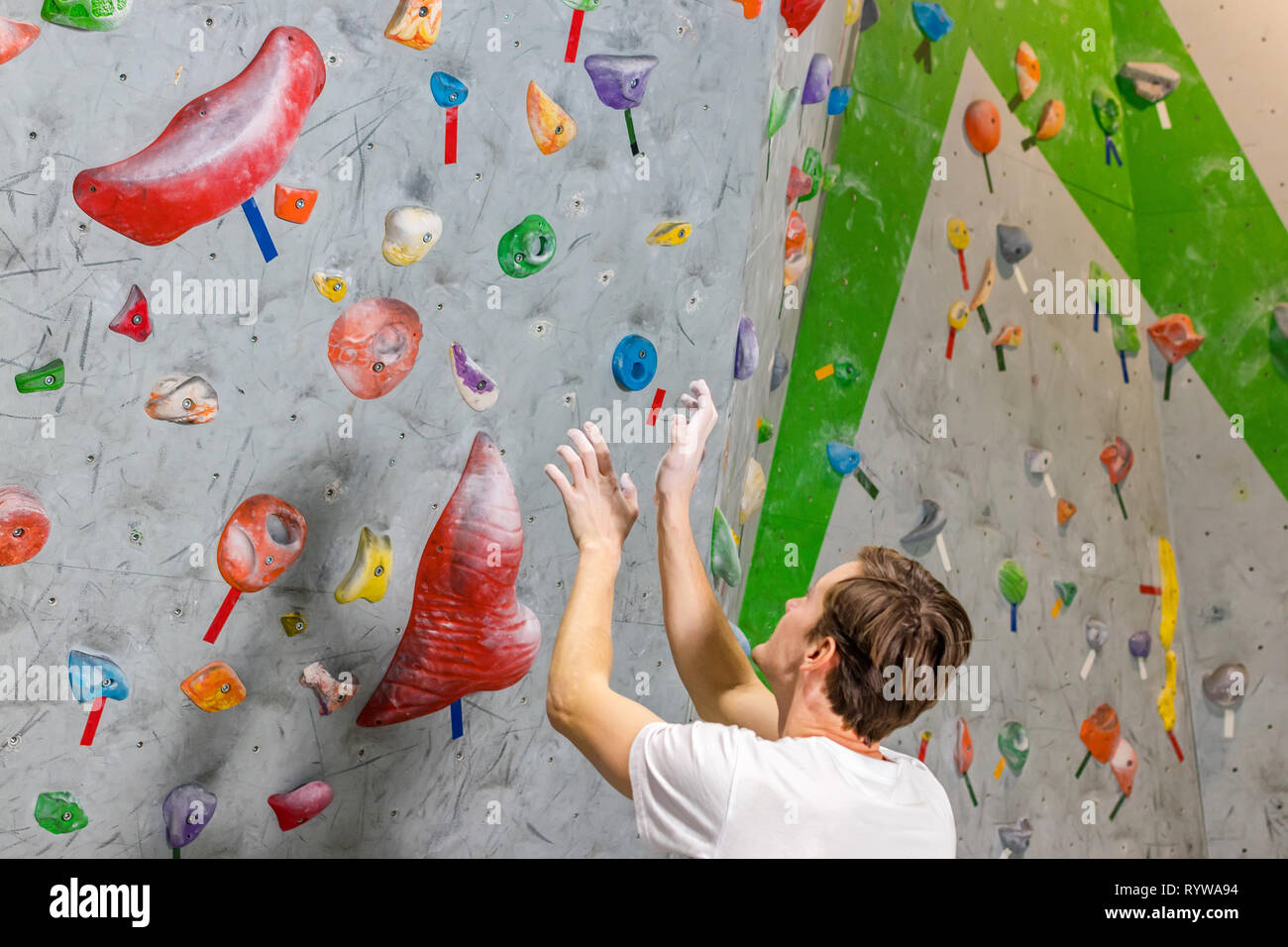 Kletterer erforscht und entwickelt eine Route auf einer Kletterwand im Boulder Halle Stockfoto