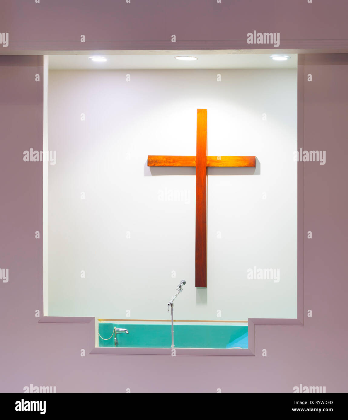 Vertikale schoss einer Kirche Baptisterium mit einem hölzernen Kreuz auf der weißen Wand dahinter. Stockfoto