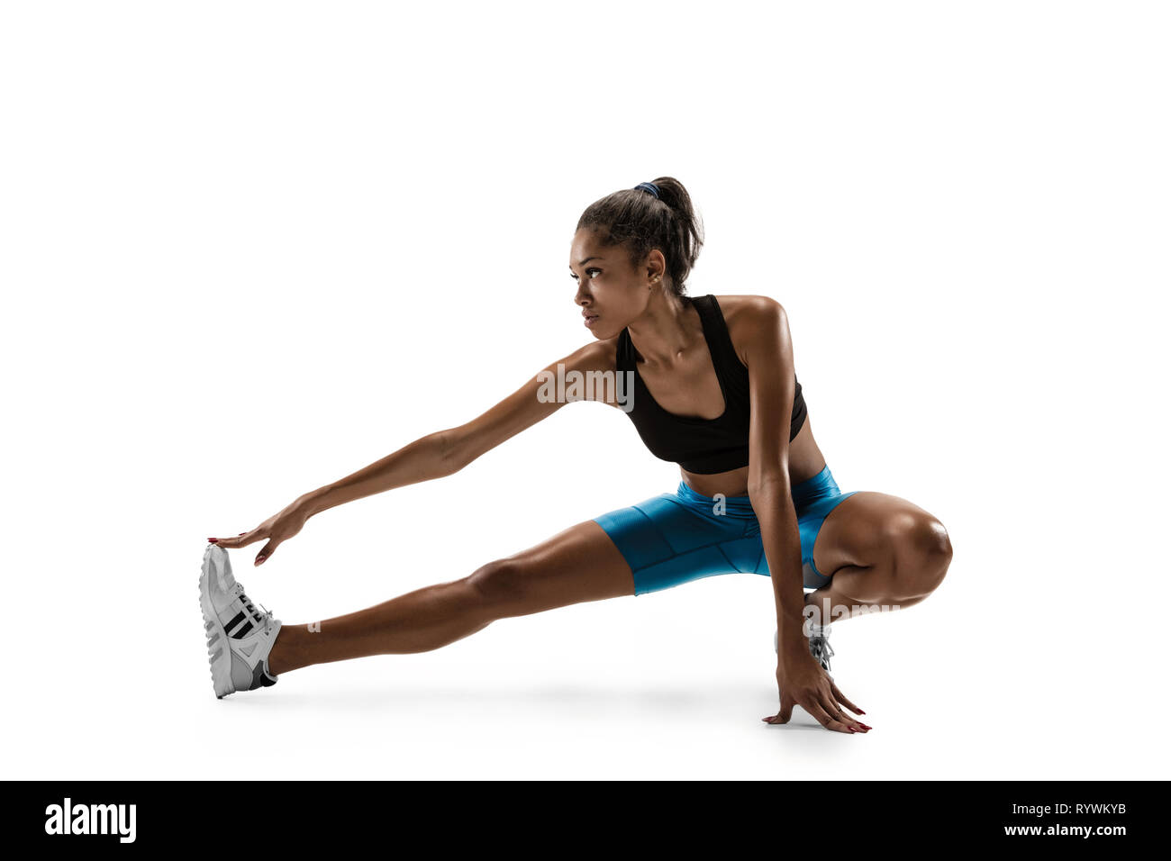 Junge afrikanische Frau Aufwärmen vor dem Laufen auf weiße studio Hintergrund isoliert. Eine Läuferin oder Jogger. Silhouette von Stretching Athlet mit Schatten. Stockfoto