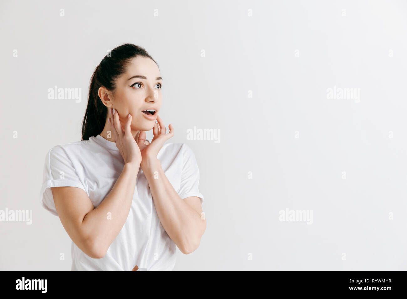 Wow. Schöne weibliche Hälfte - Länge vorne portrait isoliert auf Grau studio Hintergrund. Junge emotionale überrascht stehende Frau mit offenen Mund. Menschliche Gefühle, Mimik Konzept. Stockfoto