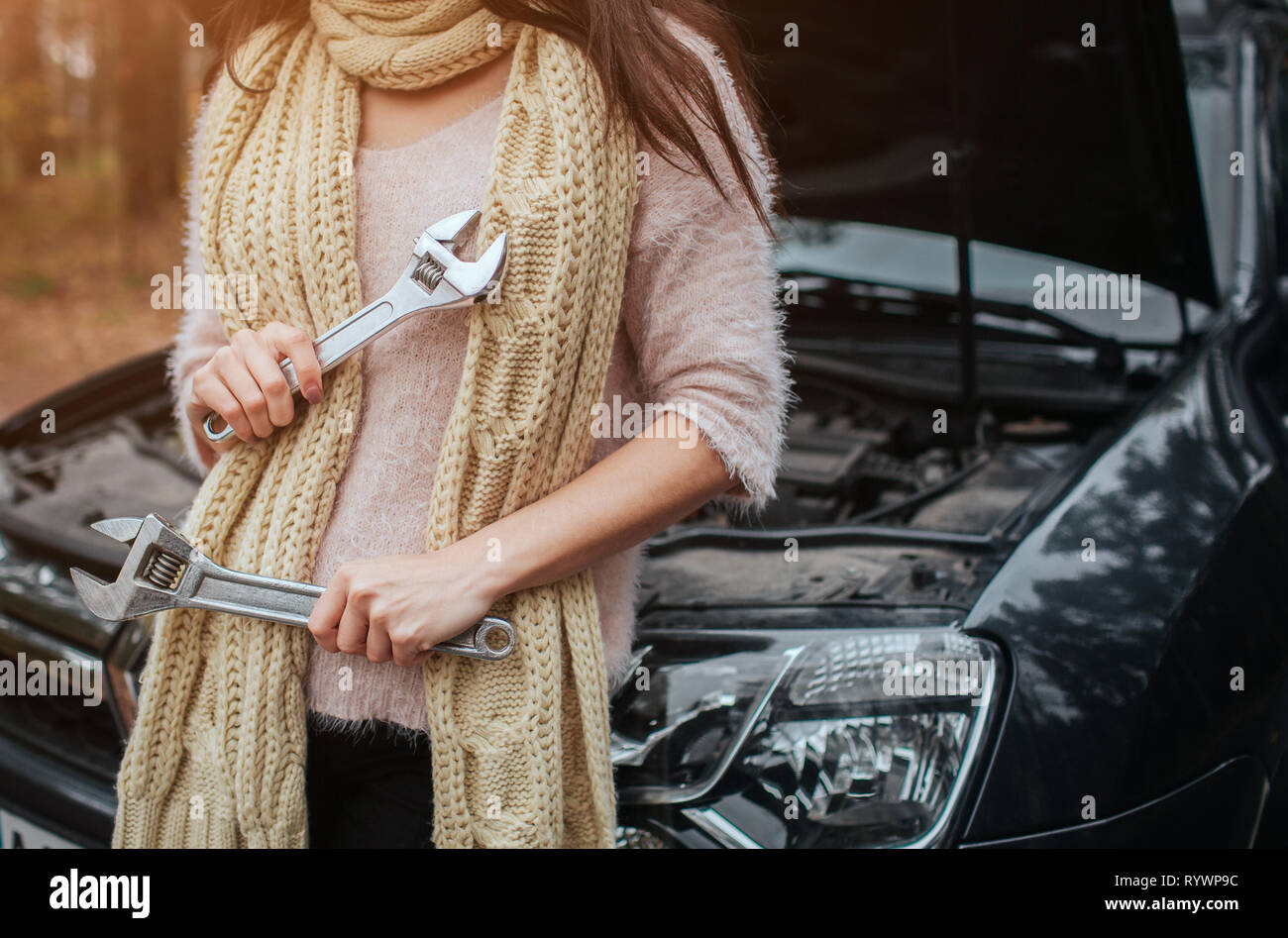 Verwirrte junge Frau auf der Suche nach Auto Motor auf der Straße Stockfoto