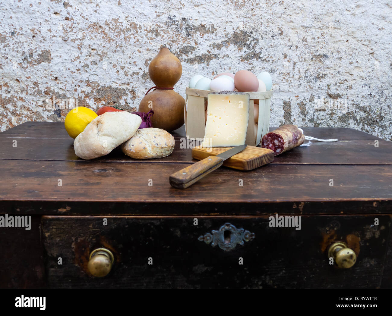 Traditionelle spanische Küche auf einem alten Holztisch, iberischen Schwein Wurst, Brot, Eier, Käse und Gemüse und ein altes Messer Stockfoto