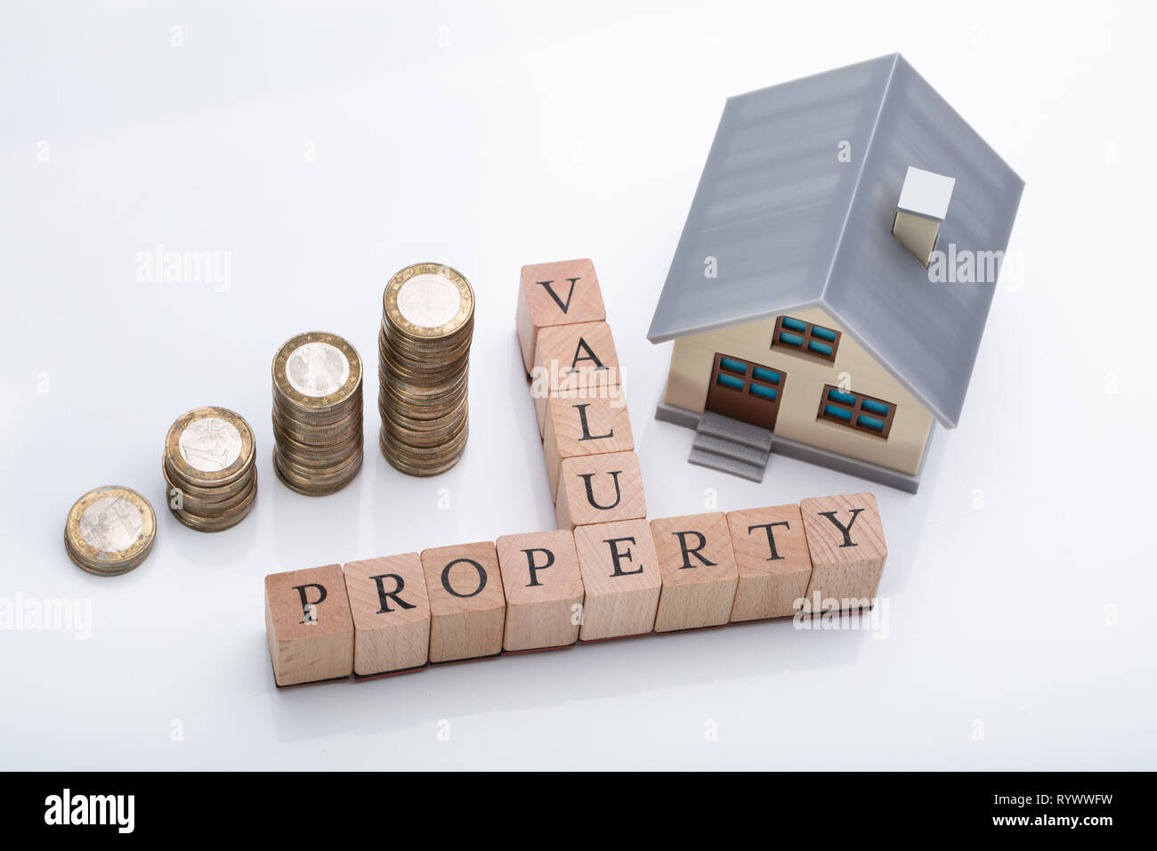 Haus Modell und gestapelte Münzen zeigen Property Value Konzept auf reflektierenden Schreibtisch Stockfoto