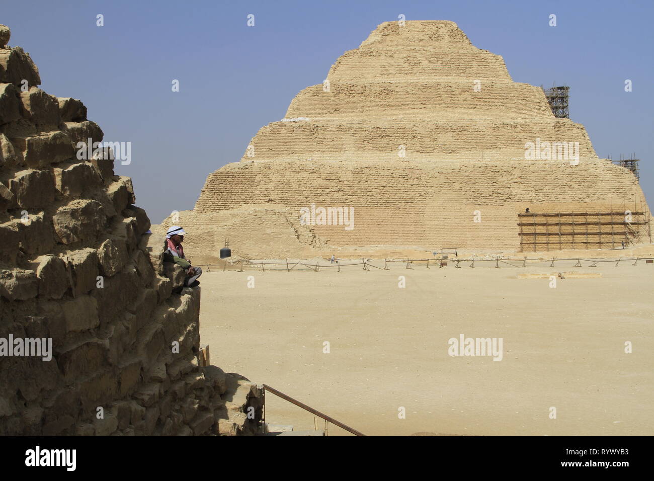Der Mensch im Vordergrund sitzend mit einem Sonnenhut, trat Pyramide des Djoser im Hintergrund, Gizeh, Sakkara Governorate, Ägypten Stockfoto