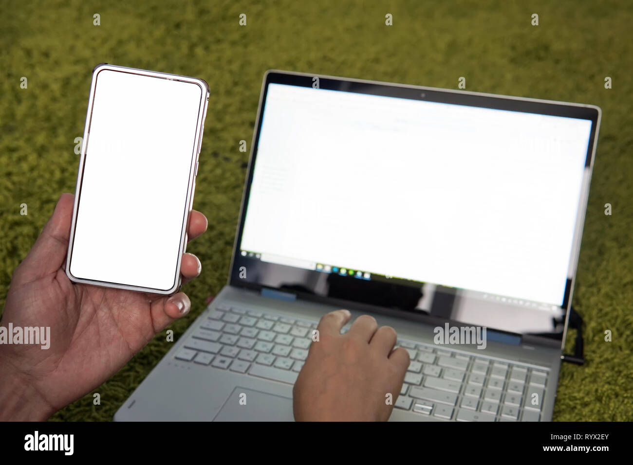 Junger Mann Arbeiten am Laptop und Smartphone zu Hause. Moderne Laptops und Handys mit weißen leeren Bildschirmen. Freelancer verwendet mobile und Wlan zu Busi machen Stockfoto