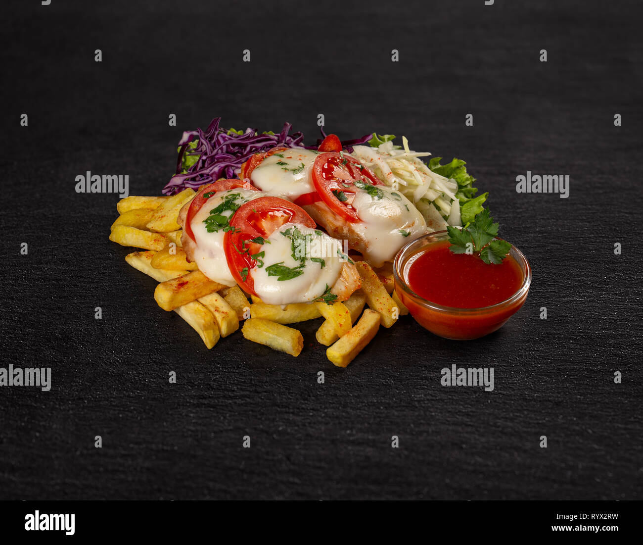 Fast Food und ungesundes Essen Konzept auf schwarzem Schiefer Hintergrund Stockfoto