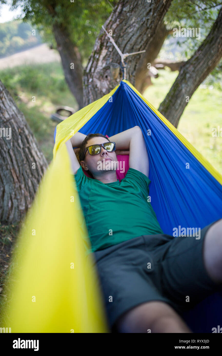 Foto des Menschen in der Sonnenbrille in der Hängematte im Wald liegen Stockfoto