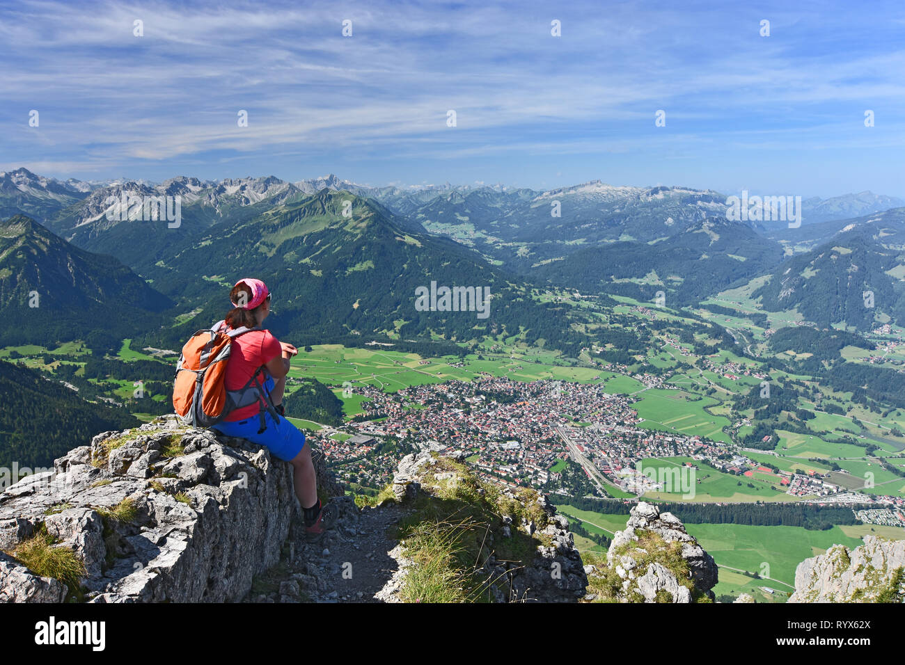 Frau sitzt auf dem Gipfel des Rubihorn Berg genießt die Aussicht auf das Bergdorf Oberstdorf und die Allgäuer Alpen. Deutschland, Österreich Stockfoto