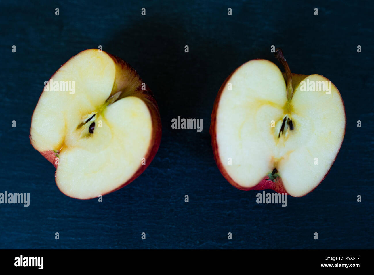 Ein roter Apfel halbiert auf einer Ebene schiefer Hintergrund Stockfoto