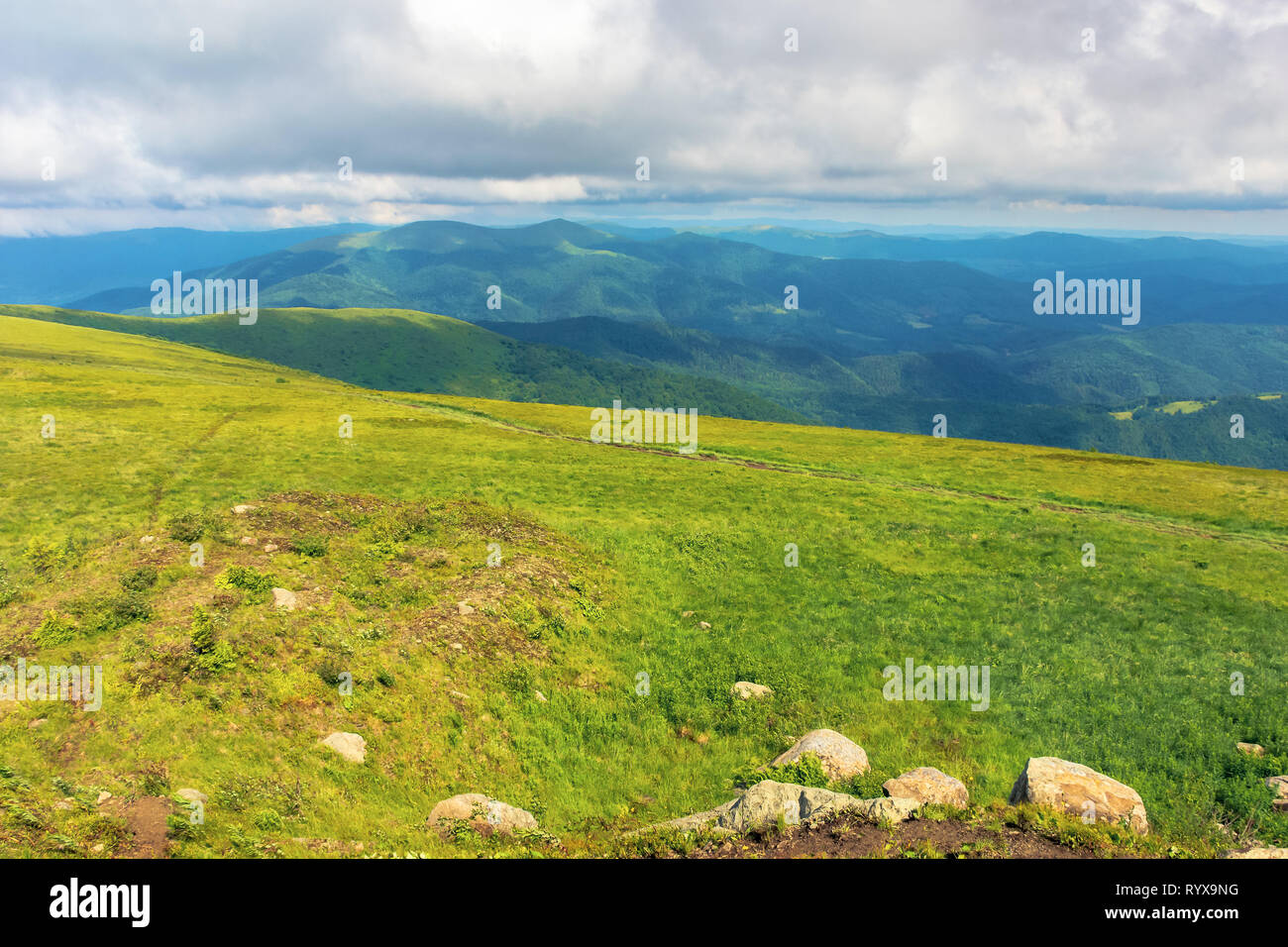 Bergwelt im Sommer mit einem bewölkten Himmel. grüne Gras Wiese mit einigen Felsen auf dem Hügel. ridge in der Ferne. schöne Karpaten natur Szen Stockfoto