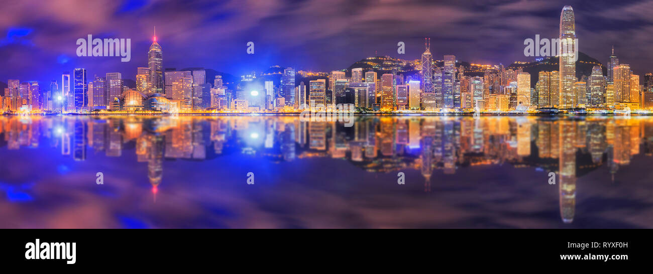 Dunkle pre-dawn Panorama in Hong Kong City auf der Hong Kong Insel CBD Wahrzeichen und hoch aufragenden Türmen gegen bewölkt blauer Himmel mit helle Beleuchtung refle Stockfoto
