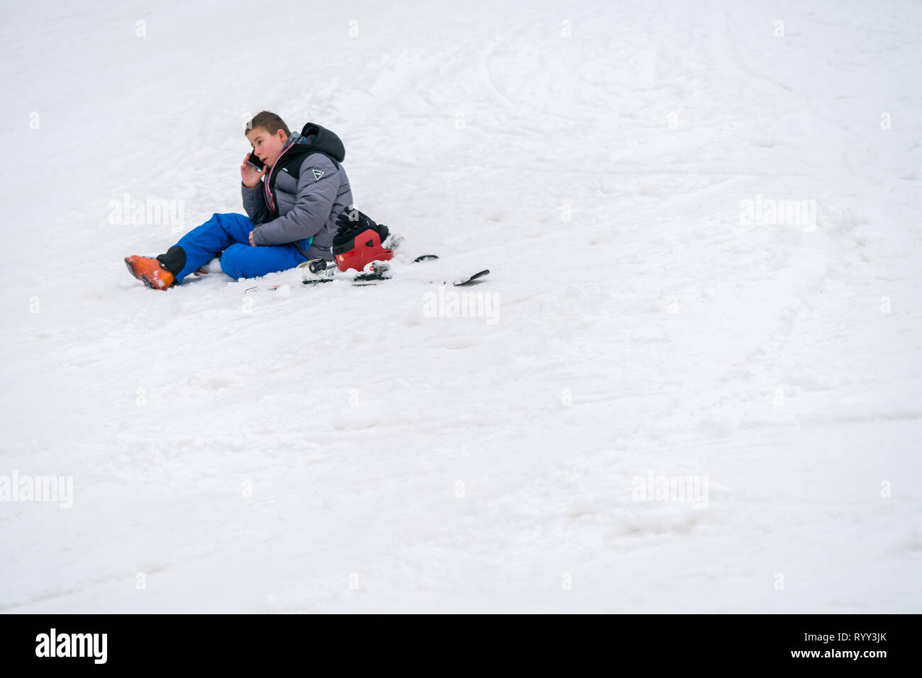 Szklarska Poreba, Polen - Februar 2019: Junge um Hilfe ruft auf seinem Handy nach dem Skifahren oder Snowboarden Unfall auf dem Berghang, Stockfoto