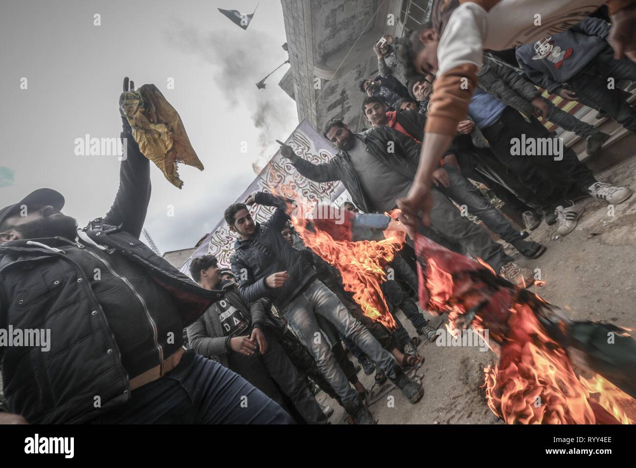 Anhänger der Opposition werden gesehen, brennenden Flaggen während der Feier. Syrer in der Stadt Bensh, die liegt östlich von Idlib und gesteuert von der Opposition, feierte den achten Jahrestag des Aufstandes gegen die Herrschaft von Präsident Baschar al-Assad. Stockfoto