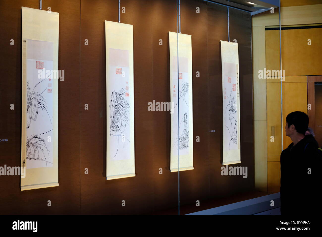 Ein Besucher vor vier hängenden Schriftrollen von Tinte Orchideen von Kaiserinwitwe Cixi der Qing Dynastie. Suzhou Museum. Suzhou in der Provinz Jiangsu. China. Stockfoto