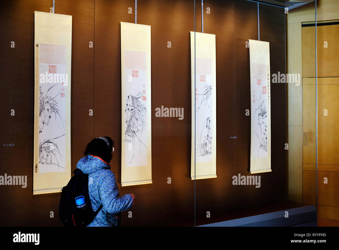 Ein Besucher vor vier hängenden Schriftrollen von Tinte Orchideen von Kaiserinwitwe Cixi der Qing Dynastie. Suzhou Museum. Suzhou in der Provinz Jiangsu. China. Stockfoto