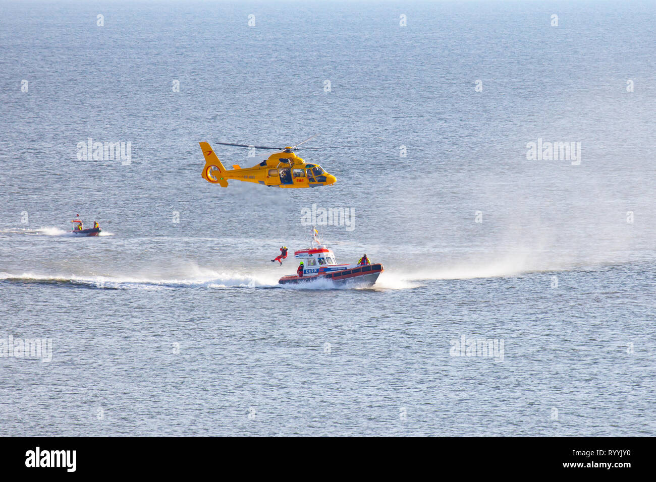 Ein Helikopter der Niederländischen coastgard ist Abseilen ein Mann über dem Meer während einer Rettung bohren Stockfoto