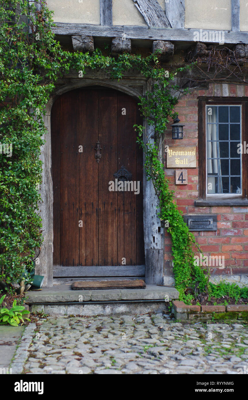 Eine hölzerne Tür zu einem Haus in Canterbury England mit Weinreben, die um die Tür krabbeln Stockfoto