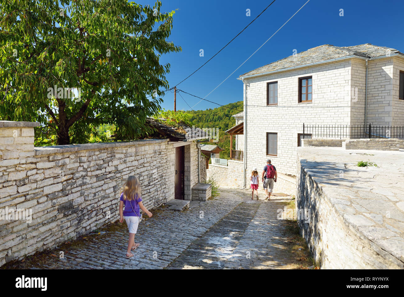 Vater und Kinder erkunden Monodendri Dorf mit seinen traditionellen, aus Stein erbaute Gebäude aus Stein und Gehwege, Zagoria Gebiet, Region Epirus, Nord-westlichen Stockfoto