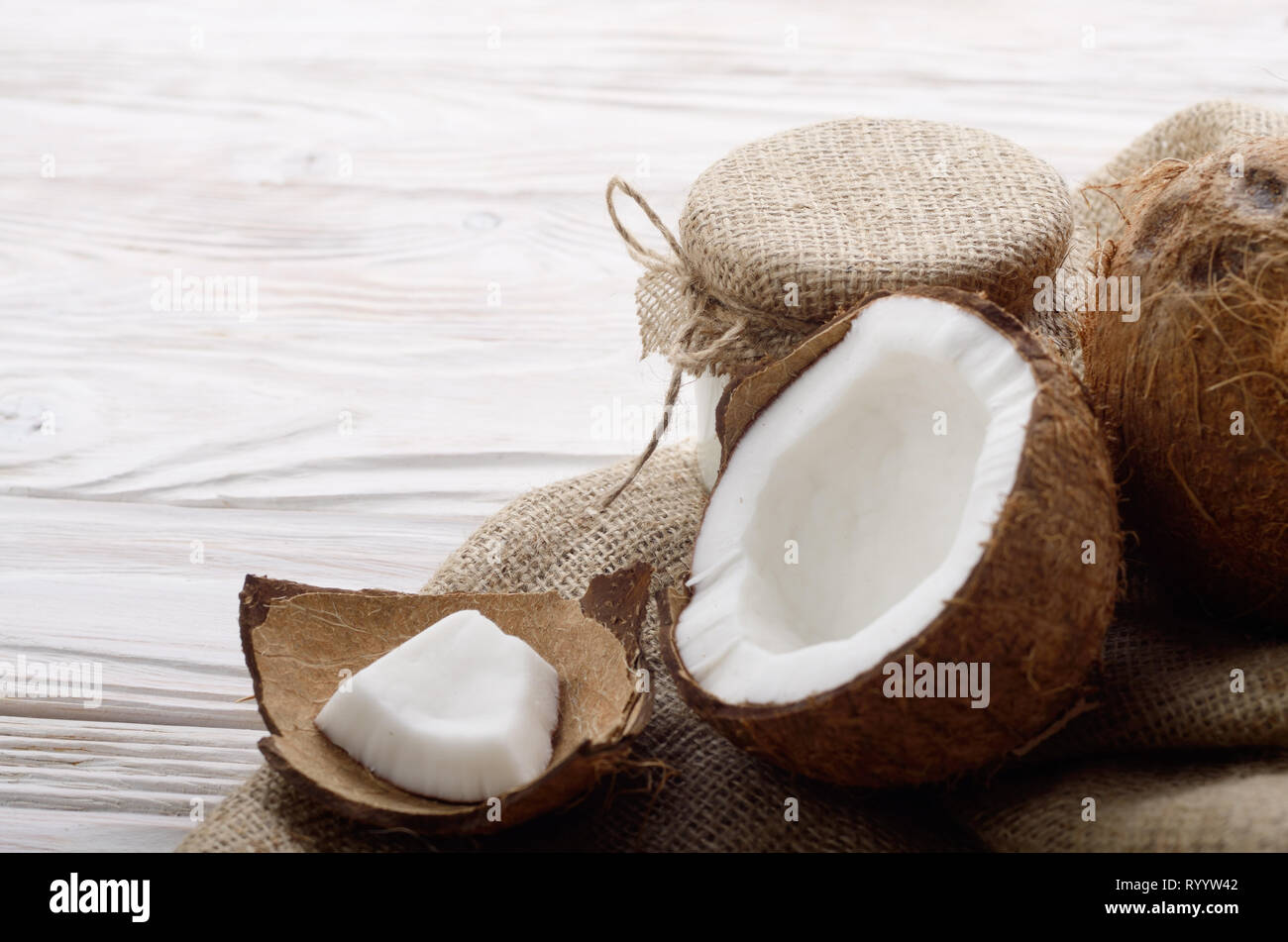 Coconut Shell mit Fleisch auf Hanf Sack auf weißen Küche aus Holz Tisch Stockfoto