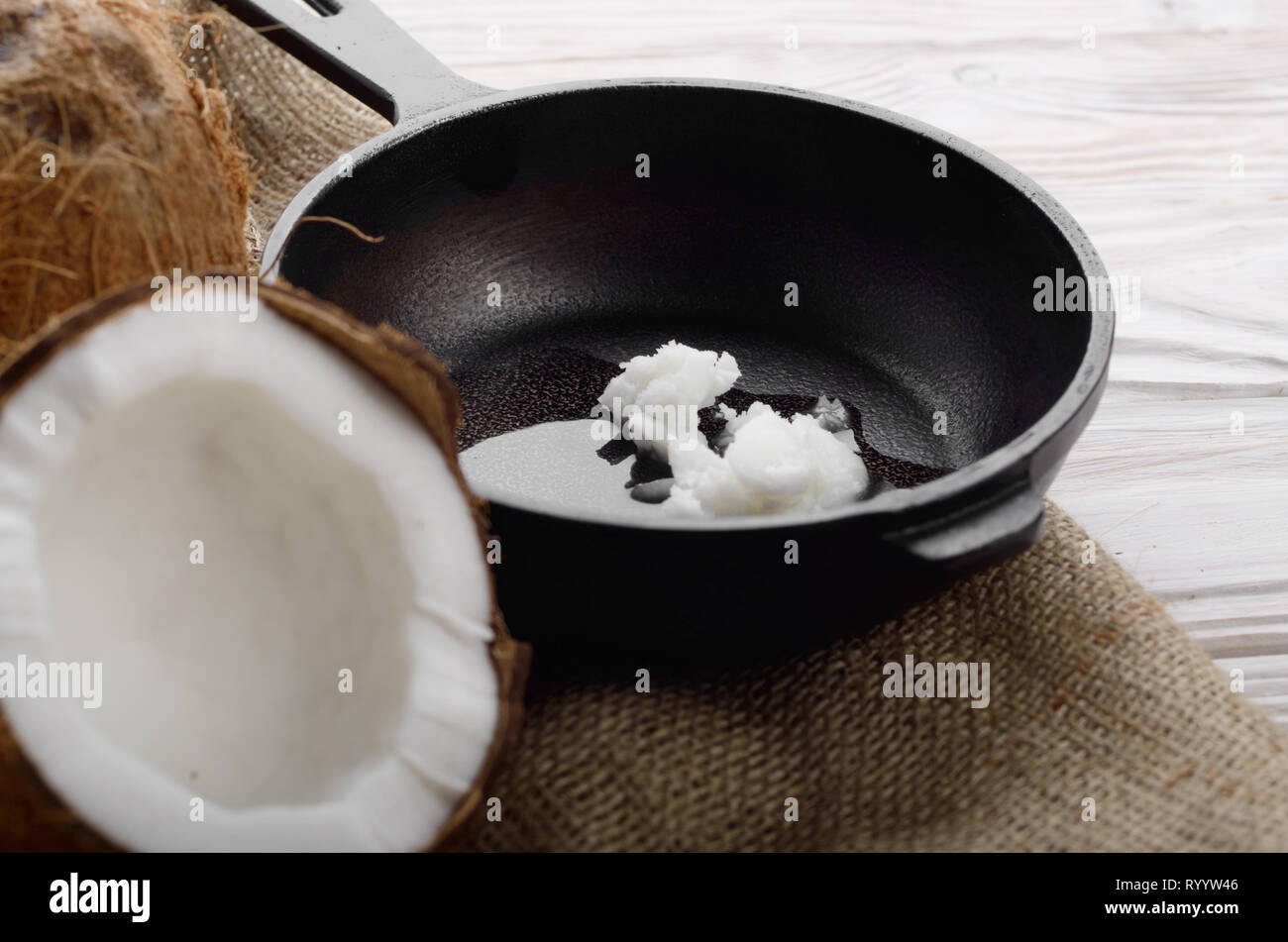 Kokosnuss, Shell mit Fleisch, Gusseisen Skillet auf Hanf Sack auf weißen Küche aus Holz Tisch Stockfoto