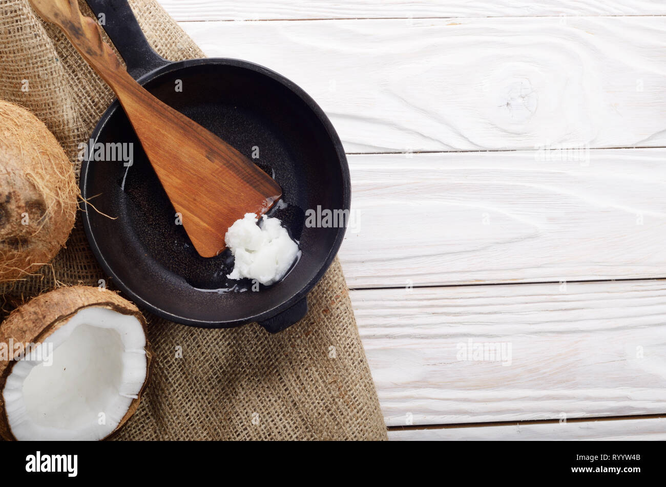 Kokosnuss, Shell mit Fleisch, Gusseisen Skillet und Spachtel auf Hanf Sack auf weißen Küche aus Holz Tisch Stockfoto