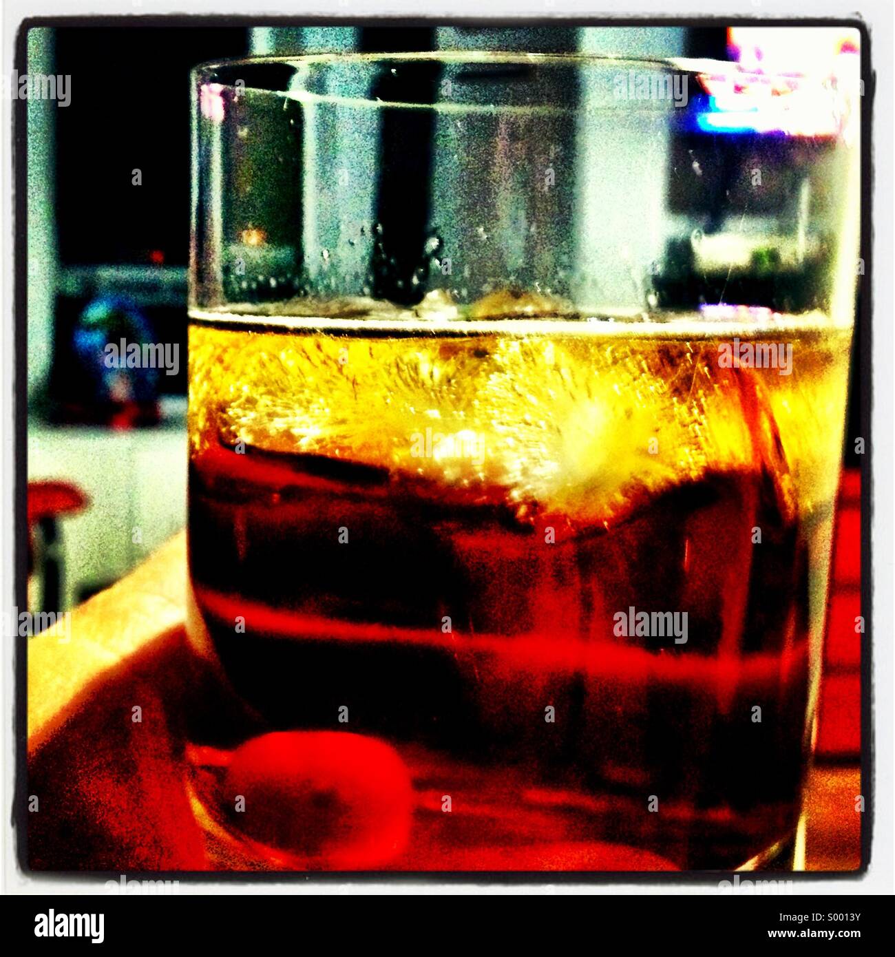 Hand hält ein Highball-Glas von einem Manhattan-Cocktail. Stockfoto
