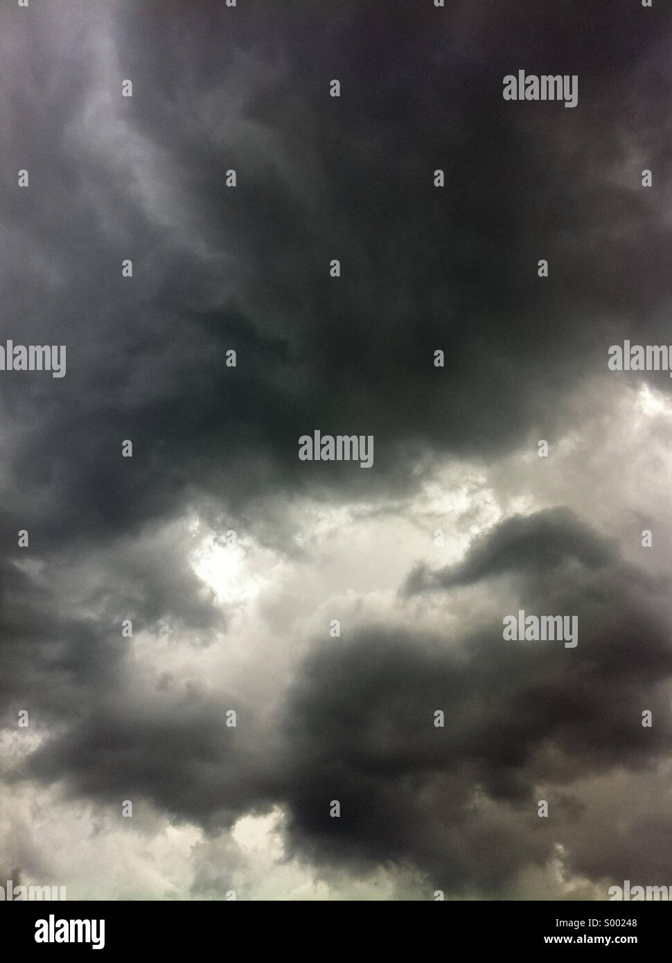 Sonnenlicht späht durch dunkle, Vorahnung Wolken in einem gewalttätigen, stürmischen Himmel. Stockfoto