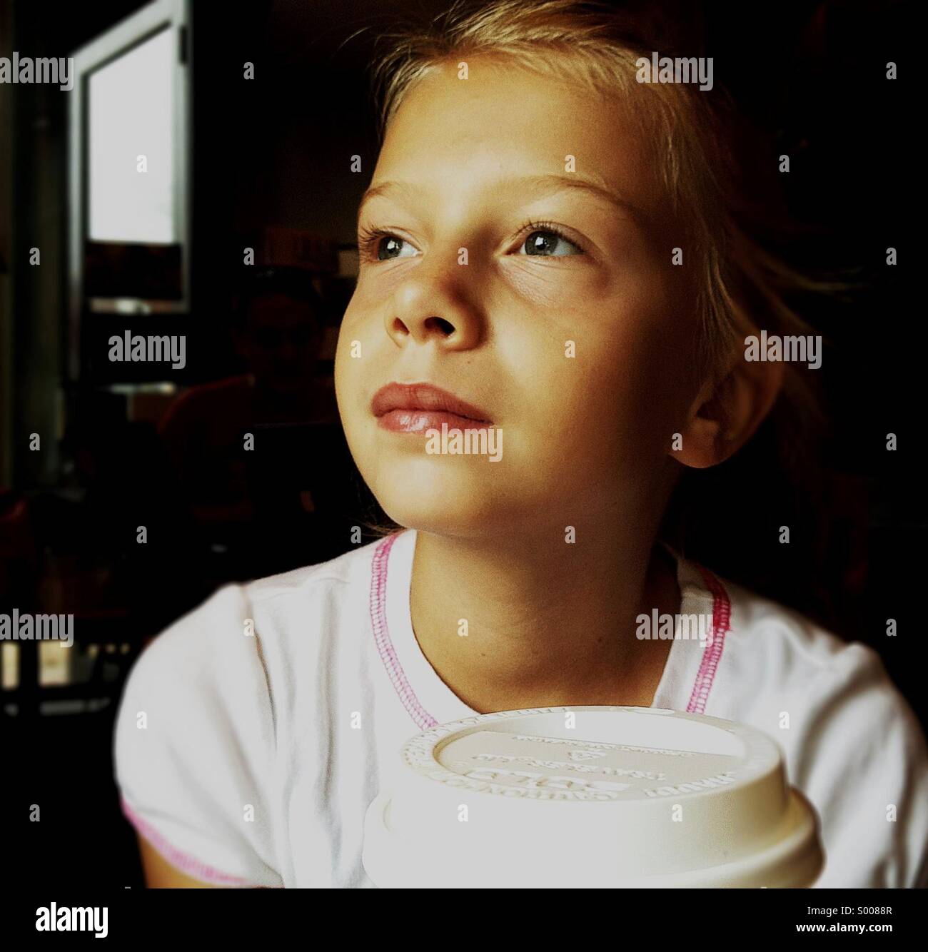 Ein junges Mädchen trinkt einen Vanille-Latte in einem Straßencafé. Stockfoto