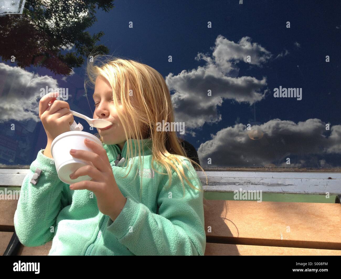 Ein kleines Mädchen bei einer Tasse Eis außerhalb wenn ein Café. Stockfoto