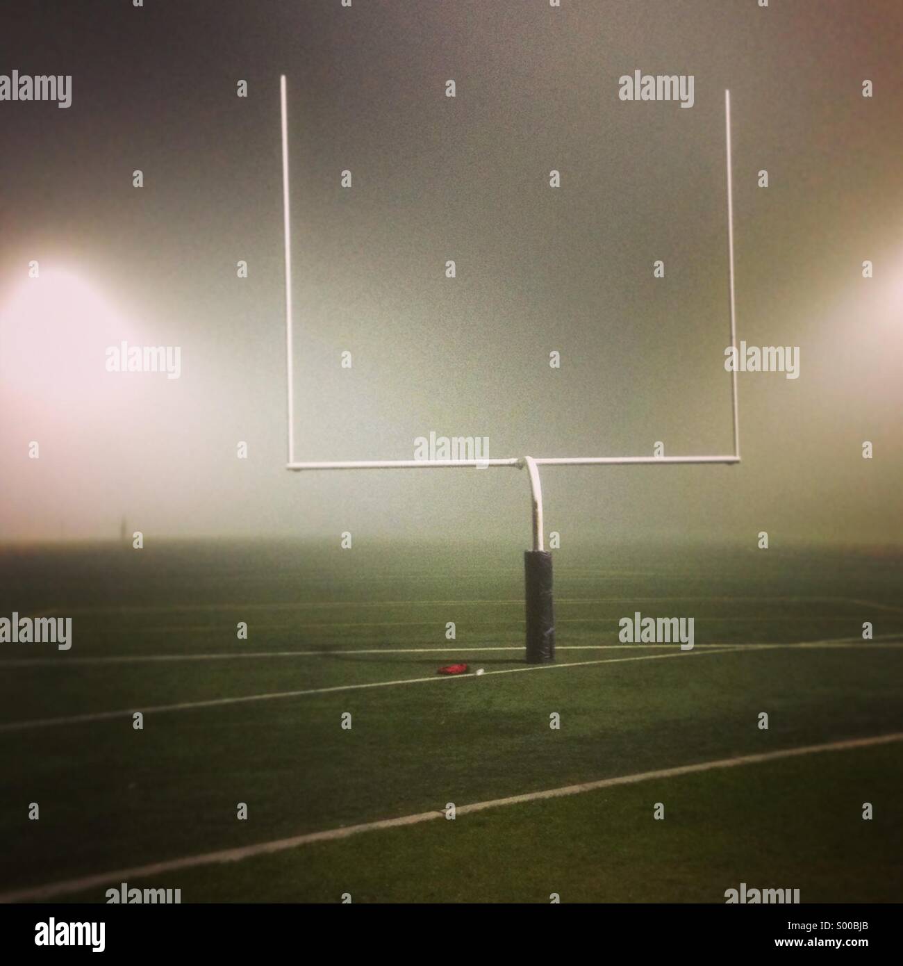 Fußballplatz und Torpfosten eingehüllt in Nebel in der Nacht Stockfoto