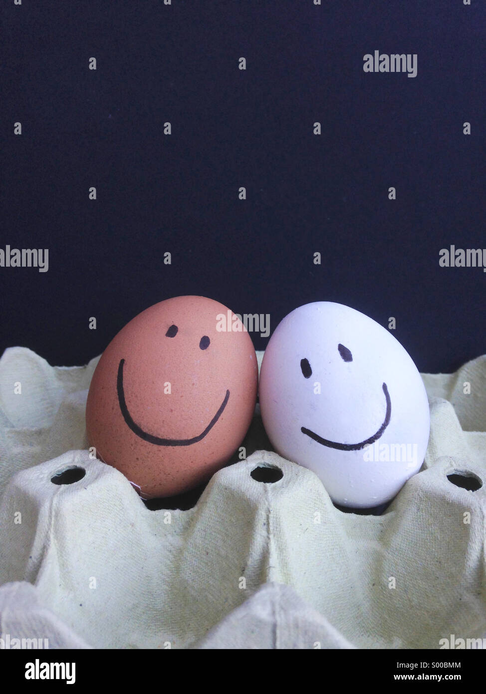 Glückliche Gesichter, braunen und weißen Eiern. Stockfoto