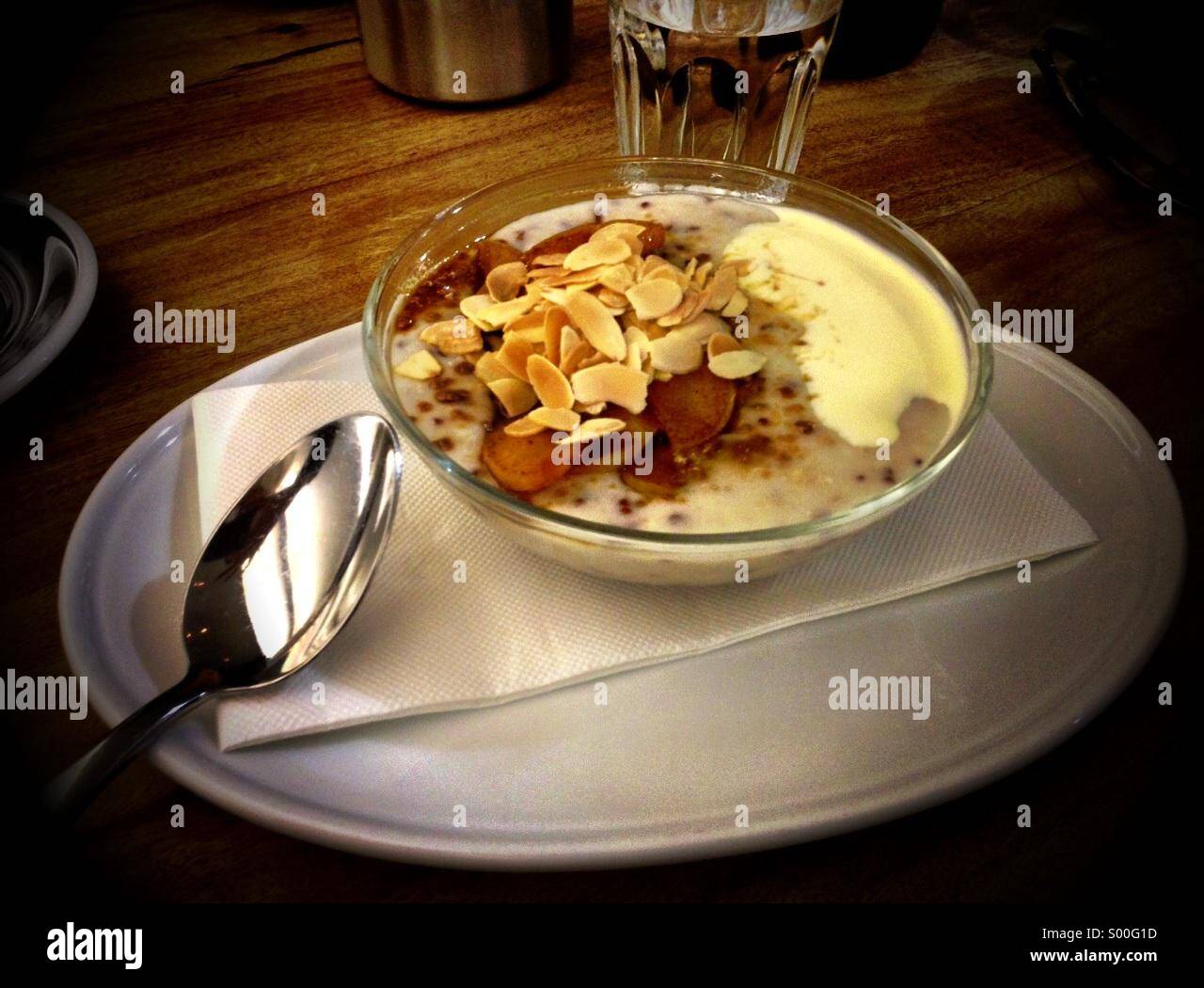 Porridge zum Frühstück mit einem Flocken Mandeln, Obst und Sahne Stockfoto