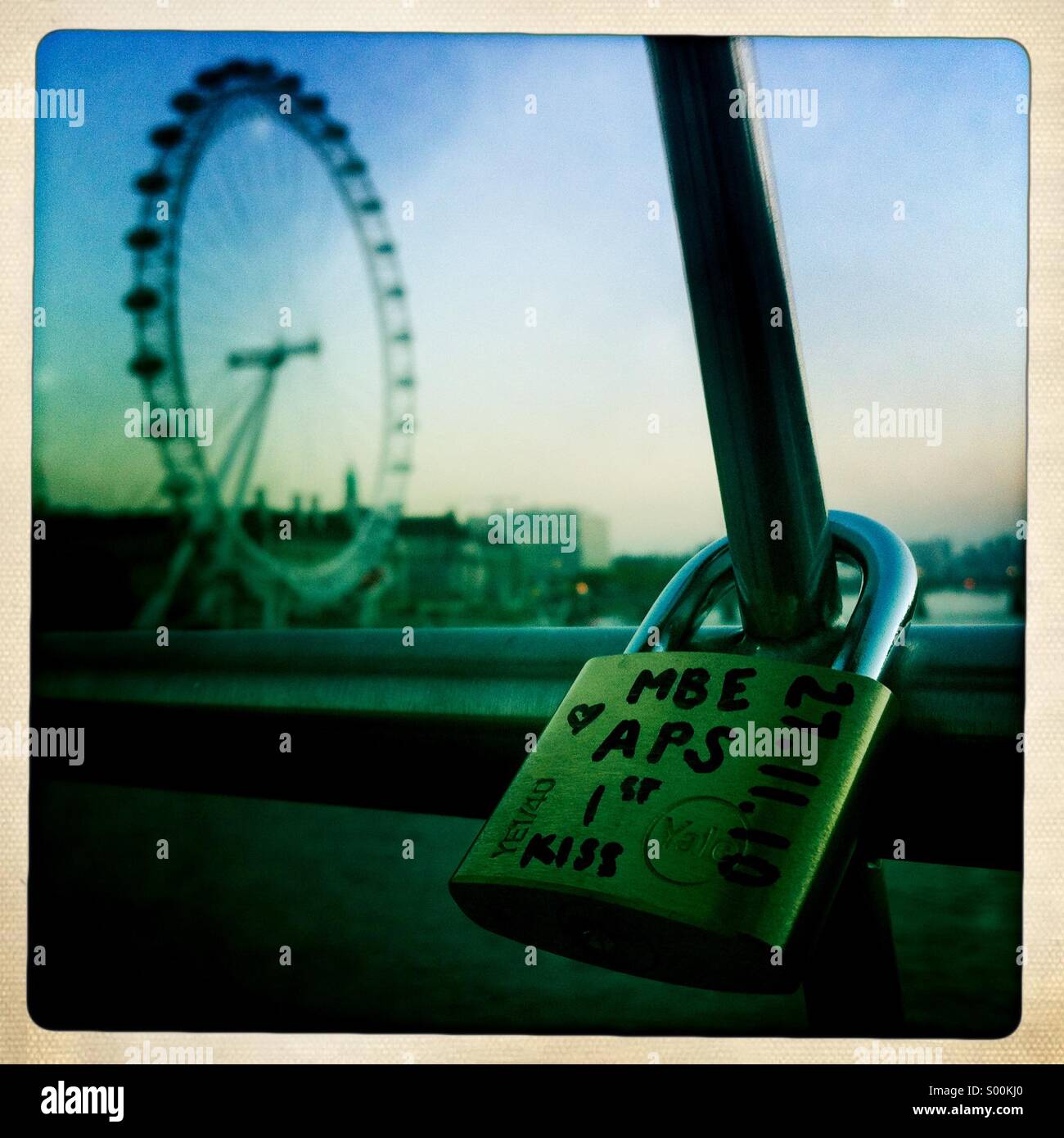 Ein Schloss als Symbol für ein Paare erster Kuss auf der Hungerford Bridge mit dem London Eye im Hintergrund. - Smartphone-aufgenommenes Stockfoto