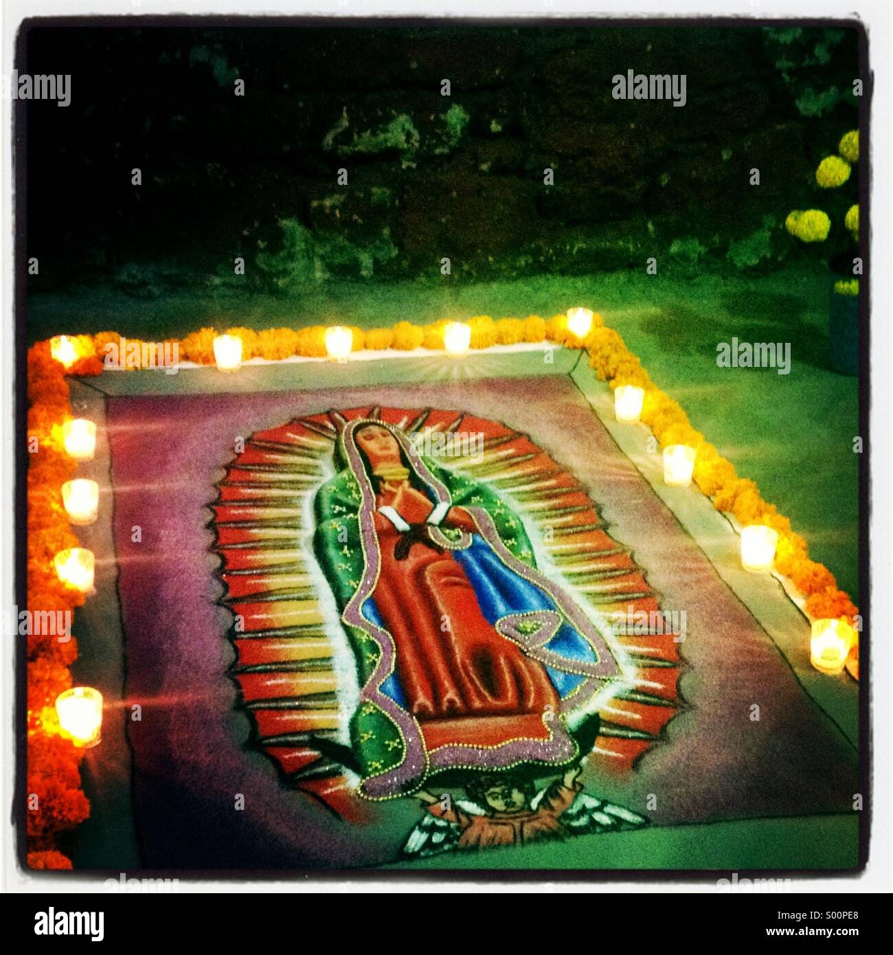Ein Sand Teppich beleuchtet mit Kerzen und mit dem Bild der Muttergottes von Guadalupe schmückt eine Straße während der Tag der Toten feiern in Santa Cruz Xoxocotlan, Oaxaca, Mexiko Stockfoto