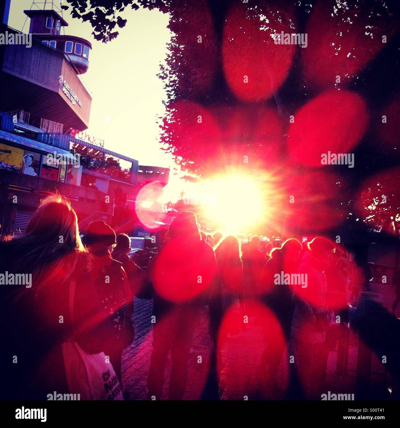 Masse der Leute Hintergrundbeleuchtung gegen Sonne mit großen roten Objektiv Flare-Effekt Stockfoto