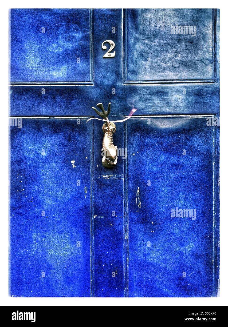 Eine helle blaue farbige Tür mit einem Fisch geformt Klopfer. Stockfoto