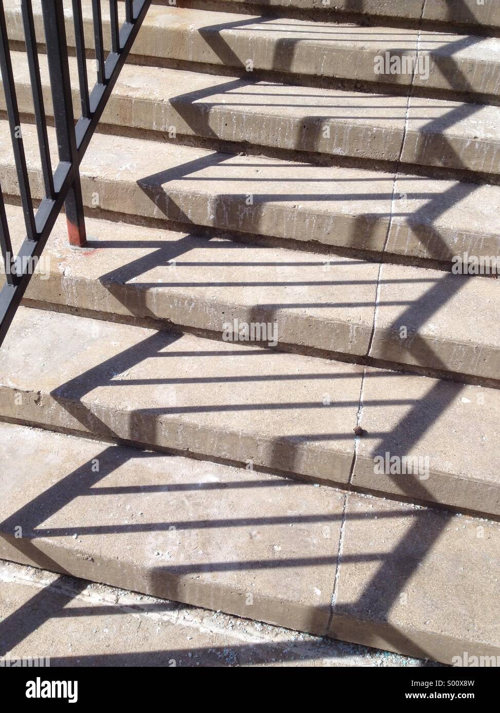 Zick-Zack-Muster der Schatten des Eisernen Geländers entlang konkrete Schritte an einem sonnigen Tag Stockfoto