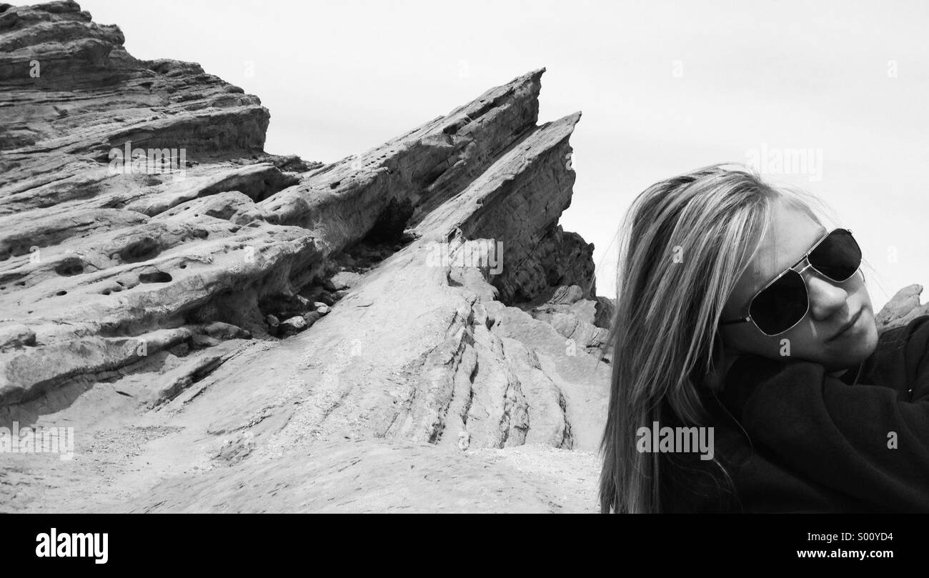 Ein junges Mädchen lehnt sich zurück nach Wüste Felsformationen hinauf. Stockfoto