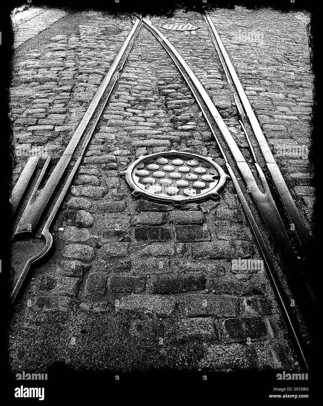 Trolley Tracks eingebettet in einer Straße mit Kopfsteinpflaster mit Schachtdeckel im Stadtteil Dumbo Brooklyn NY. Stockfoto