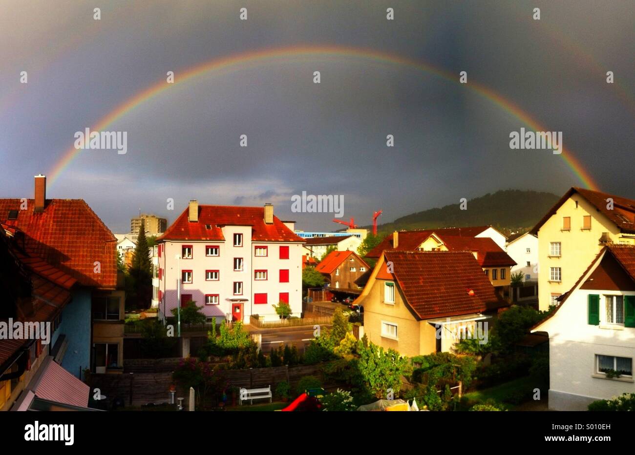 Doppelter Regenbogen über Häuser und Gärten in Liebefeld, einer Wohngegend von Bern, Schweiz Stockfoto