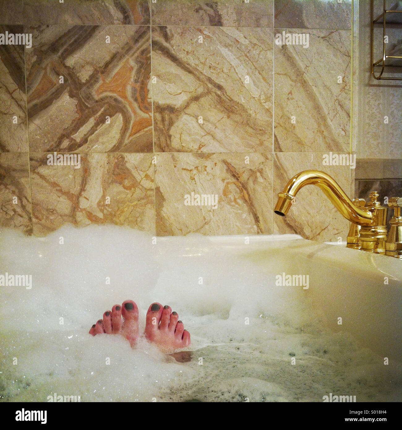 Eine Frau Zehen Peek, von ein entspannendes Schaumbad in einem ausgefallenen Badewanne Stockfoto