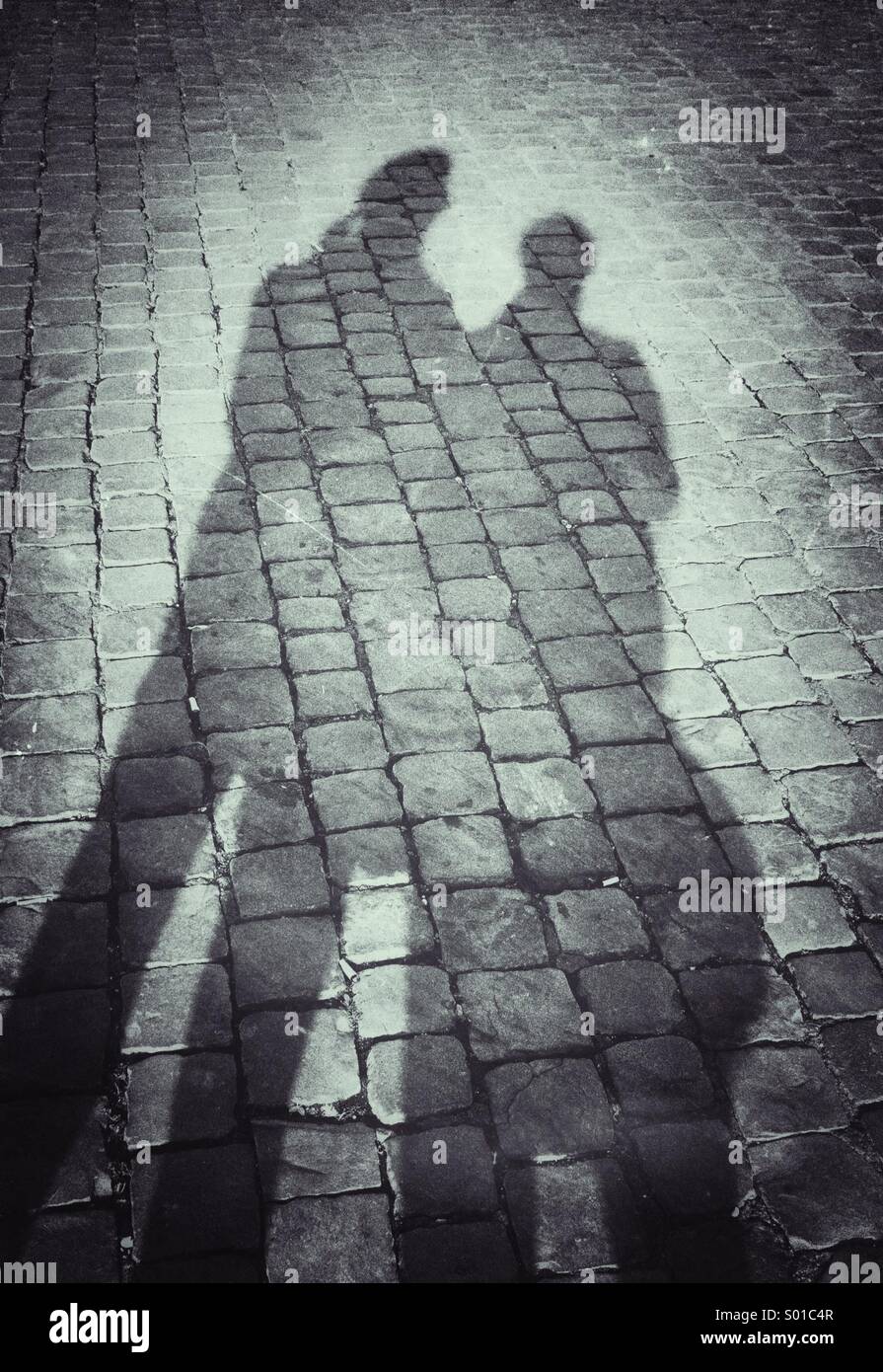 Schatten von Mann und Frau auf Kopfsteinpflaster Stockfoto