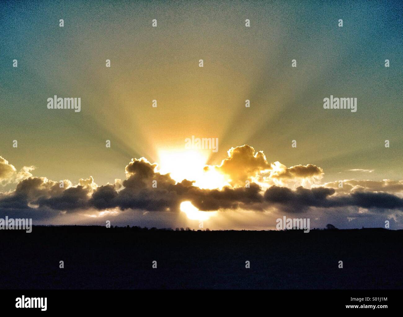 Sonnenstrahlen hinter Wolken in der Dämmerung / Dämmerung Stockfoto