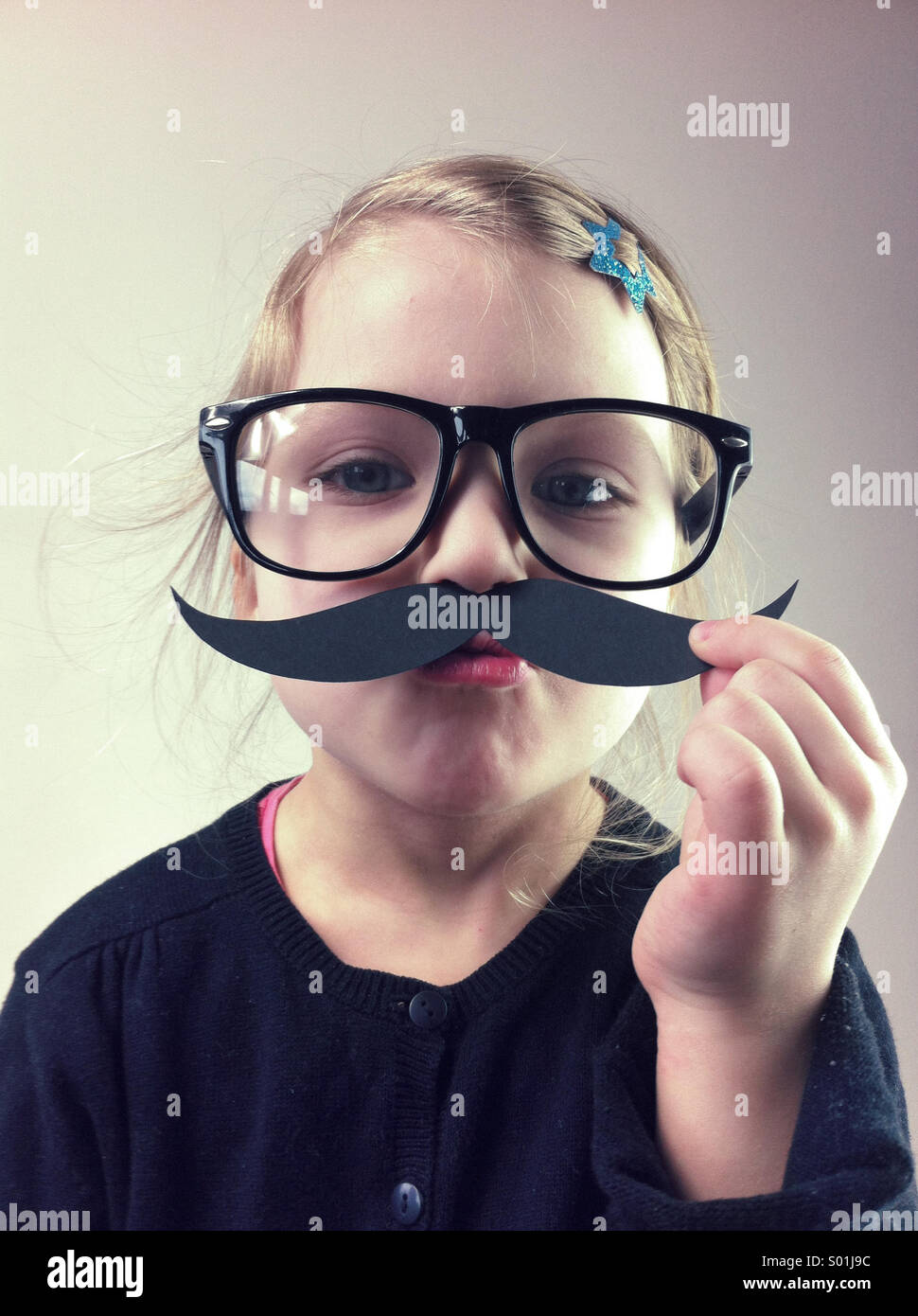 Kleines Mädchen mit großen Gläsern und Papier Schnurrbärte Stockfoto