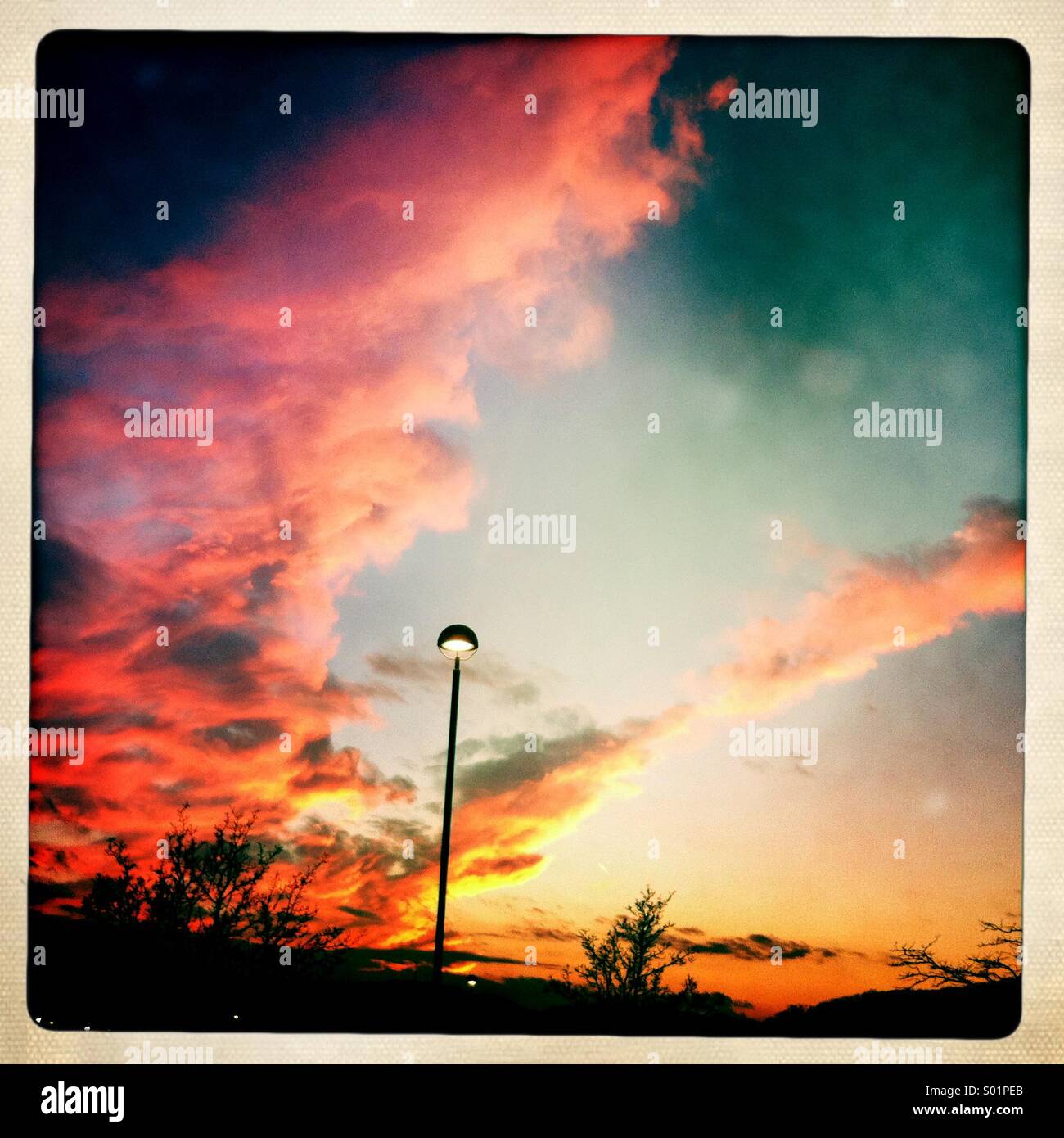 Einsamen Straßenlaterne gegen eine lebendige Sonnenuntergang Himmel. Stockfoto