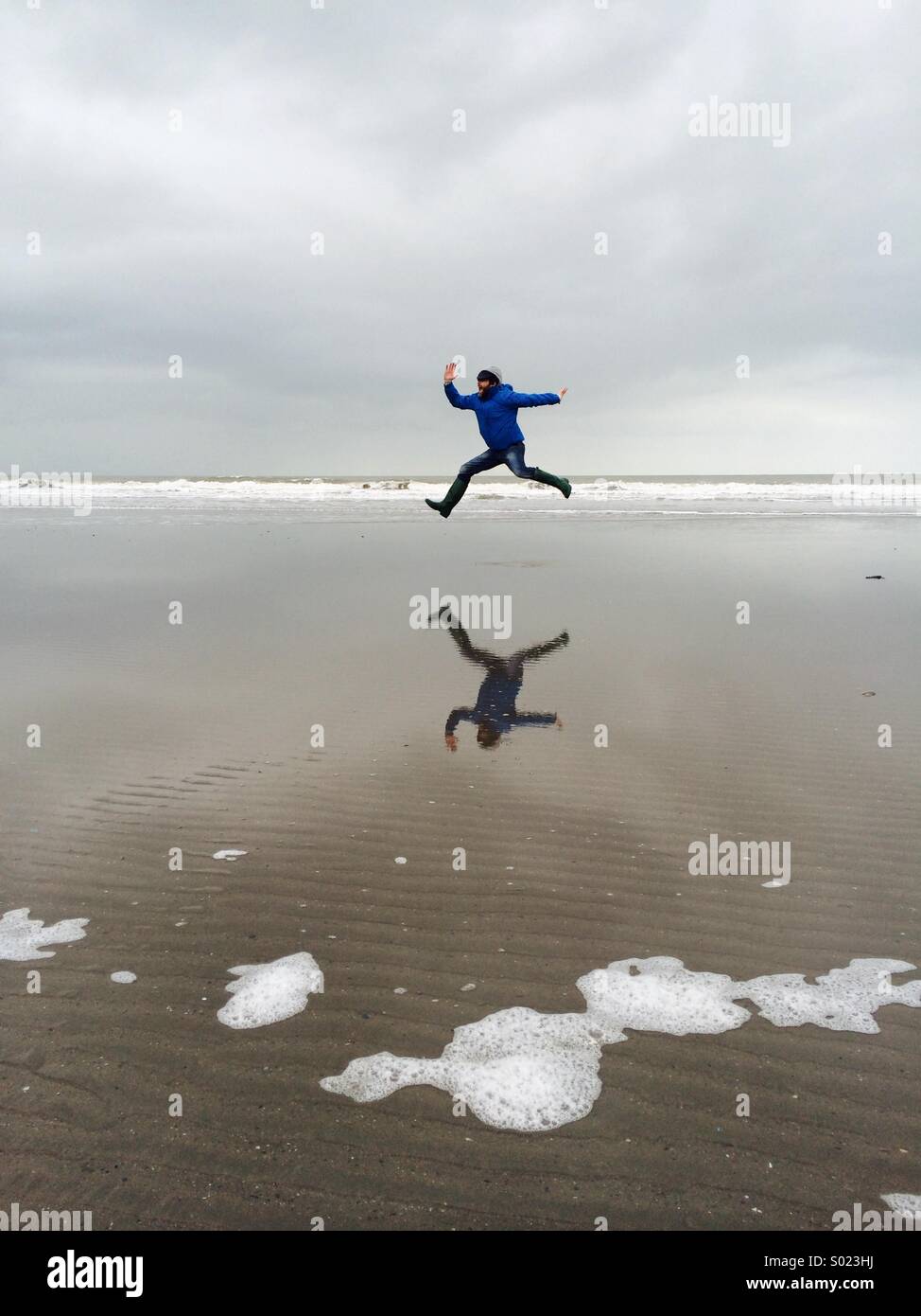 Mann springt am Strand Stockfoto