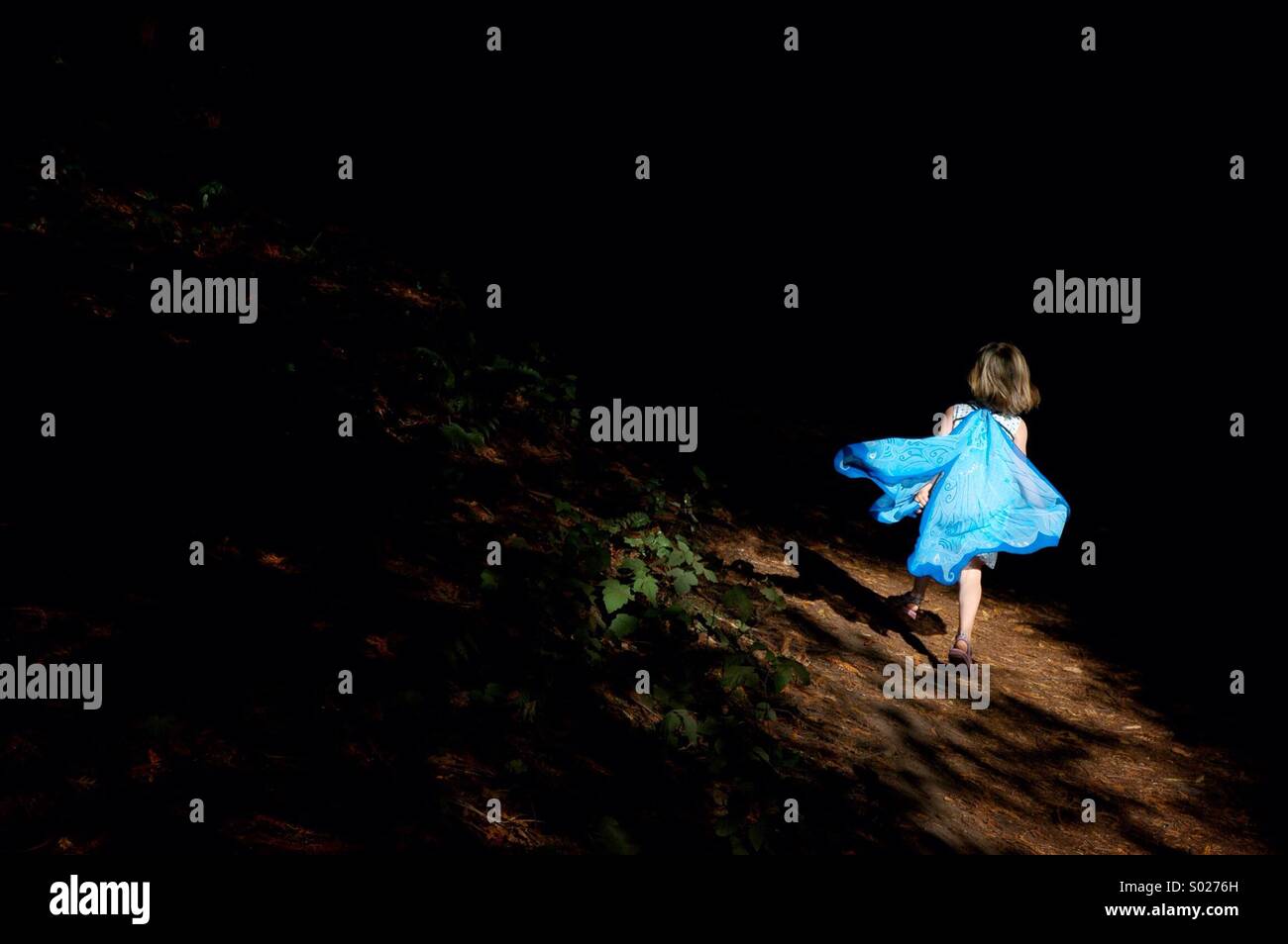 Ein kleines Mädchen läuft durch den Wald in eine Fee Kostüm. Stockfoto