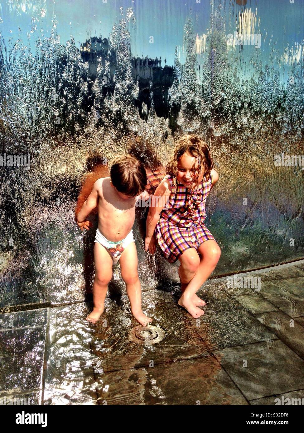 Kinder, die Spaß - und auf der Suche nach schelmischen - spielen in einem Brunnen Stockfoto