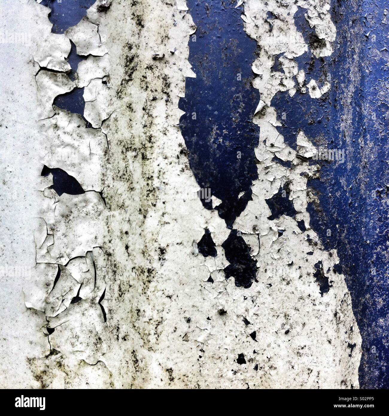 Abgesplittete Farbe legt die strukturierte Oberfläche einer alten Wand frei und zeigt eine Mischung aus Farben. Die Schälschichten sprechen von jahrelanger Exposition gegenüber den Elementen - Smartphone-aufgenommenes Stockfoto