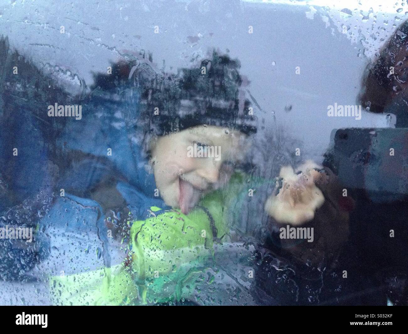 Kind-Porträt über nasse Fenster in regnerischen Tag Stockfoto